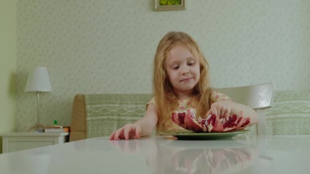 Felice bambina con i capelli biondi mangia melograno, concetto di cibo sano, ritratto ravvicinato — Video Stock