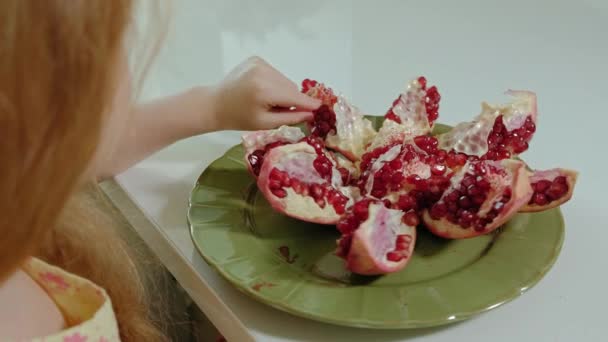 heureuse petite fille aux cheveux blonds mange de la grenade, concept de nourriture saine, gros plan 