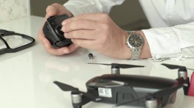 Olgun adam gözlük ve beyaz bir gömlek bir quadrocopter, teknoloji, bir el close-up incelenmesi için bir kavram için bir kontrol paneli monte