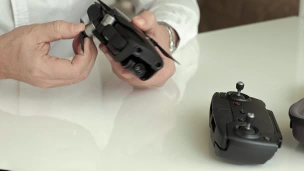 Mature man in glasses and a white shirt assembles a quadrocopter, puts forward a paddle, concept of studying technology, close-up — Stock Video