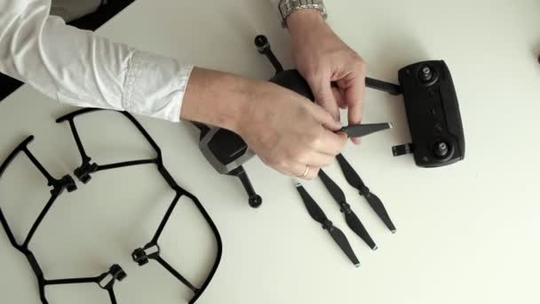 Volwassen man met bril en een wit overhemd assembleert een quadrocopter, wijzigingen messen, het concept van leren technieken, bovenaanzicht — Stockvideo