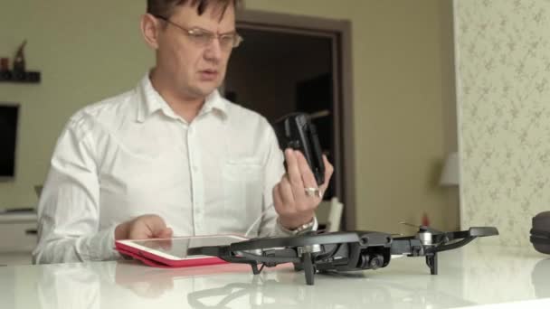 Homme mûr en lunettes et une chemise blanche assemble un quadrocopter, relie les contrôles, le concept de technologie d'apprentissage — Video