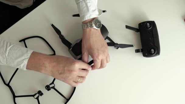 Volwassen man met bril en een wit overhemd assembleert een quadrocopter, wijzigingen messen, het concept van leren technieken, bovenaanzicht — Stockvideo