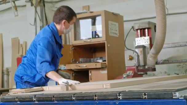 Un hombre trabaja en una fresadora, prepara espacios en blanco de madera para la puerta, la producción de puertas interiores del pueblo — Vídeo de stock