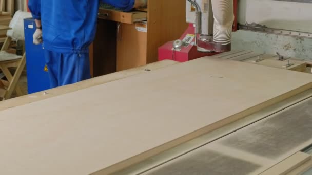 Ein Mann arbeitet an einer Fräsmaschine, bereitet Holzrohlinge für die Tür vor, die Herstellung von Dorfinnentüren — Stockvideo
