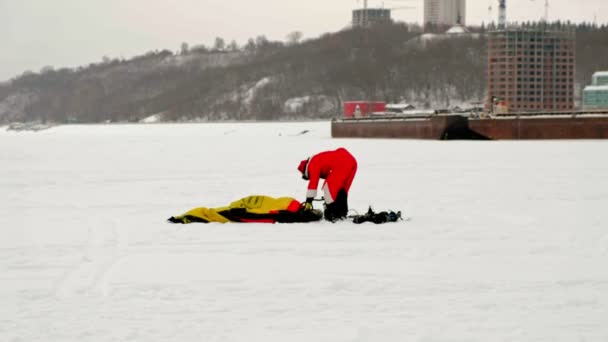 CHEBOKSARY, RUSIA - 31 DE DICIEMBRE DE 2018: un atleta que practica snowkiting, en invierno con un traje de Papá Noel, bombea aire al paracaídas — Vídeos de Stock