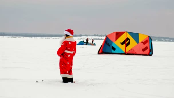 CHEBOKSARY, RÚSSIA - DEZEMBRO 31, 2018: Atleta de snowkiting, no inverno em um terno de Papai Noel, levanta o paraquedas para o céu — Vídeo de Stock