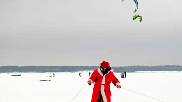 CHEBOKSARY, RÚSSIA - DEZEMBRO 31, 2018: snowkiting atletas passeio no rio em trajes de Papai Noel no inverno — Vídeo de Stock