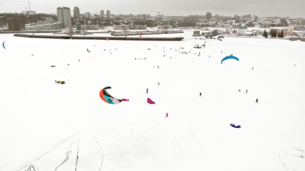 CHEBOKSARY, RUSIA - 31 DE DICIEMBRE DE 2018: Atletas involucrados en el snowkiting, en el paseo de invierno en el río con los disfraces de Santa Claus, fotografía aérea de un quadrocopter — Vídeos de Stock