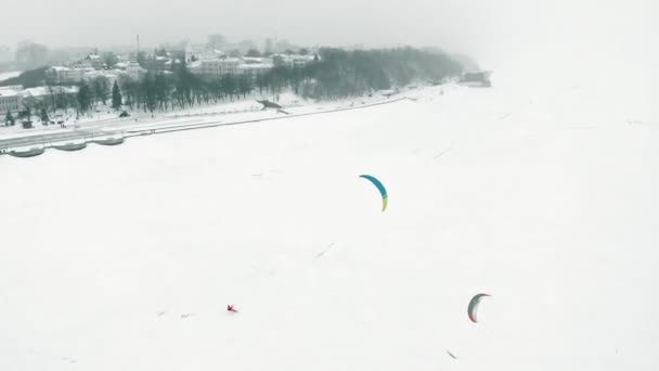 Snowkiting athletes ride on the river in Santa Claus costumes in winter — Stock Video