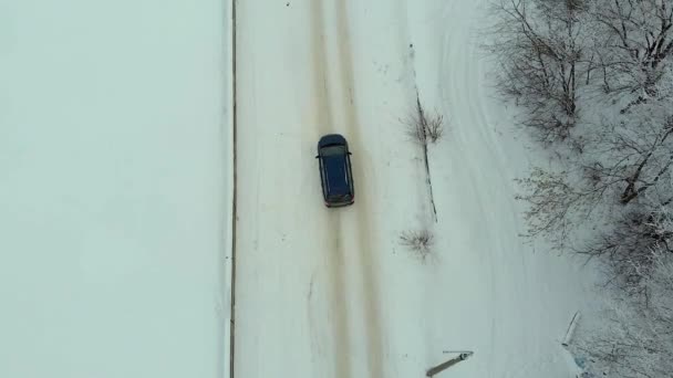 Autem na zimní venkovské silnici v zasněženém lese, letecký pohled z dronu — Stock video