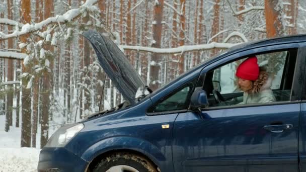 Vrouw met een stro auto op de weg in de winter — Stockvideo