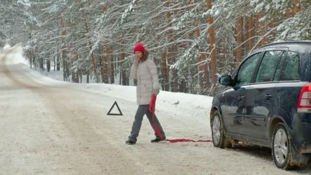 Vrouw met een stro auto op de weg in de winter — Stockvideo