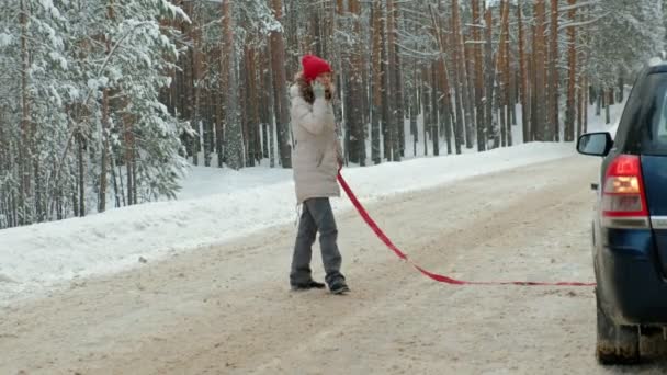 Kvinna med en halm bil på vägen i vinter — Stockvideo