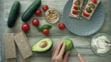 Avokado sandviç için dilimleme eller. Sağlıklı vejetaryen sandviç, çeşitli sebze ve Yeşiller ile mutfak masası. Pişirme arka plan, üstten görünüm