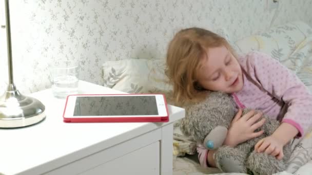 Kleines Mädchen spielt im Bett auf Tablet — Stockvideo