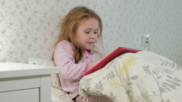 Kleines Mädchen spielt im Bett auf Tablet — Stockvideo