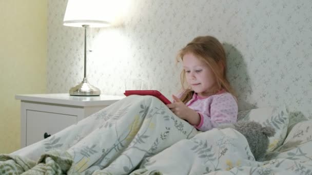 Petite fille au lit jouant sur tablette — Video