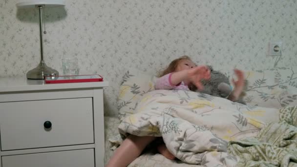 Μικρό κορίτσι στο κρεβάτι το παιχνίδι στο tablet — Αρχείο Βίντεο