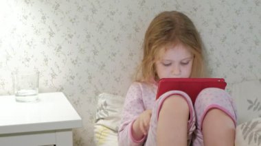 küçük kız yatakta tablet üzerinde oynama