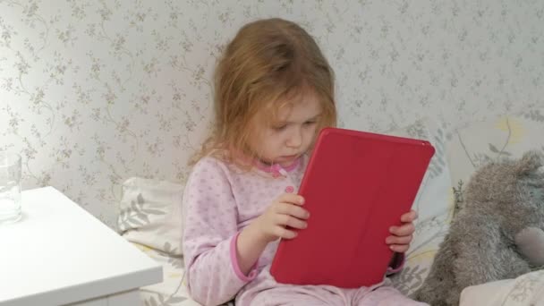 Little girl in bed playing on tablet — Stock Video