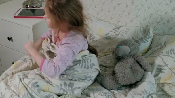 Kleines Mädchen spielt im Bett auf Tablet — Stockvideo