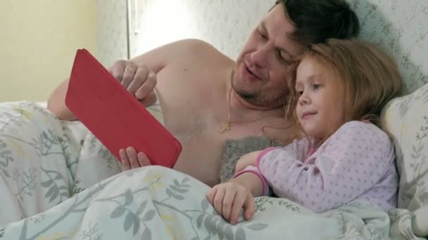 Táta a malou dceru na posteli hraje na tabletu — Stock video