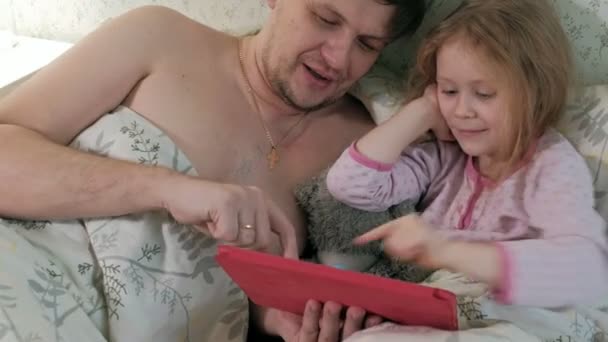 Pai e filha na cama brincando no tablet — Vídeo de Stock