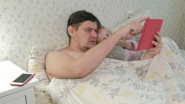 Papa et petite fille sur le lit jouant sur la tablette — Video