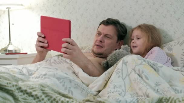 Apa, és a kislányom az ágyon, játszik a tabletta — Stock videók