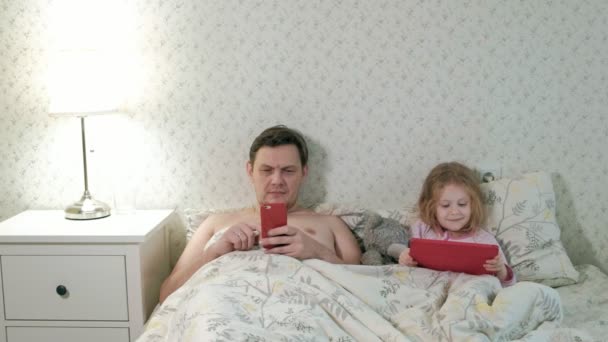 Padre e hija pequeña en la cama jugando en la tableta — Vídeo de stock