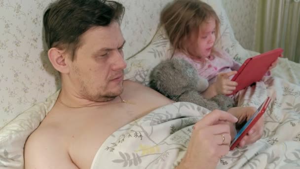 Papà e figlioletta sul letto a giocare sul tablet — Video Stock