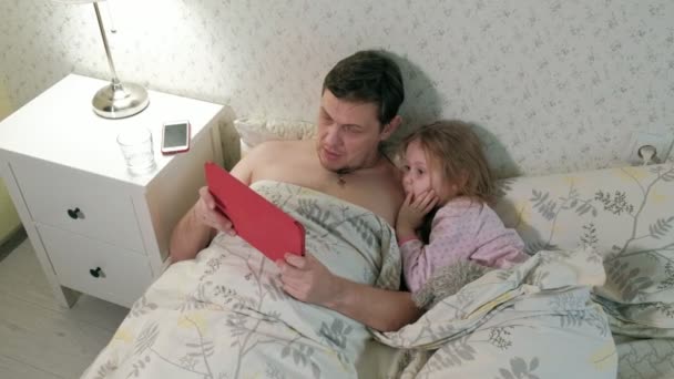 Padre e hija pequeña en la cama jugando en la tableta — Vídeos de Stock