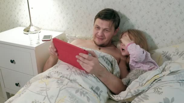 Father Little Daughter Bedtime Lying Bed Covered Blanket Use Tablet — Stock Video