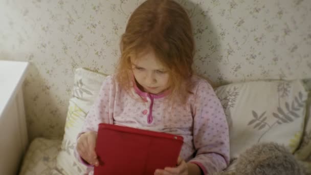 Niña en la cama jugando en la tableta — Vídeos de Stock