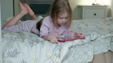 küçük kız yatakta tablet üzerinde oynama