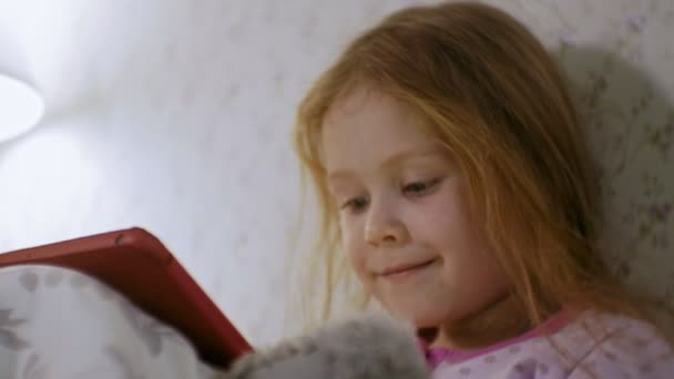 Küçük kız yatakta tablet üzerinde oynama — Stok video