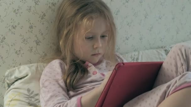 Kis lány az ágyban, játszik a tabletta — Stock videók