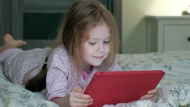 Niña en la cama jugando en la tableta — Vídeo de stock