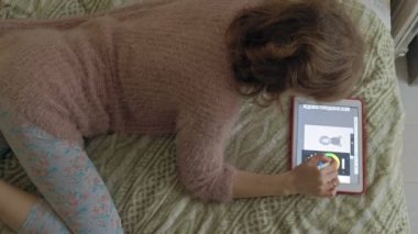Mutlu kız müzik ve evde yatak odasında bir tablet kullanarak ekran kalemi ile çizer. Web sörf, mesafe çalışma anlayışı, serbest meslek