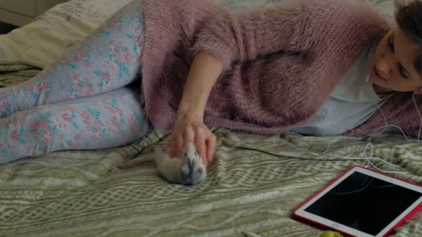 Evde, komik bir sıçan ile oynayan ve onu besleyen genç kadın — Stok video