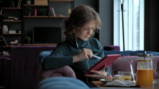 Приваблива молода жінка з планшетом у кафе, концепція фрілансера — стокове відео