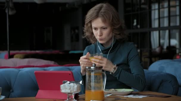 Atraktivní mladá žena s tabletem v kavárně, na volné noze koncepce — Stock video