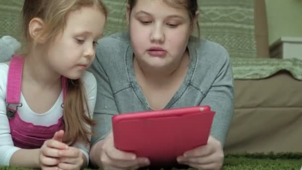 Girls sisters playing on the tablet in the room, web surfing, rest — Stock Video