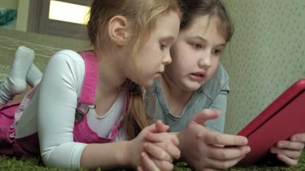 Дівчата сестри грають на планшеті в кімнаті, веб-серфінг, відпочинок — стокове відео
