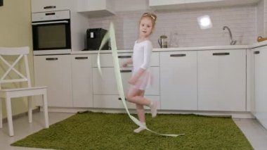 Mutlu küçük kız beyaz bir jimnastik mayo trenler, Kurtlarla dans ritmik jimnastik, atlar ve profesyonel çalışmaları gerçekleştirmek için bir şerit.