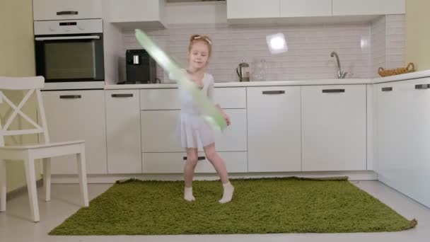 Une petite fille heureuse en maillot de bain blanc s'entraîne, danse avec un ruban pour la gymnastique rythmique, saute et fait des exercices professionnels . — Video