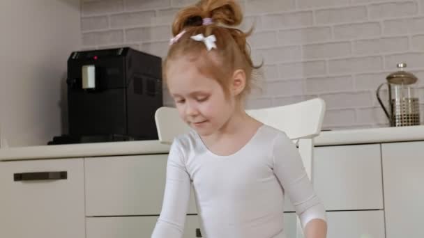 A boldog kicsi lány fehér torna fürdőruha vonatok, táncok, ritmikus gimnasztika, ugrások és szakmai gyakorlatok végrehajtása szalaggal. — Stock videók