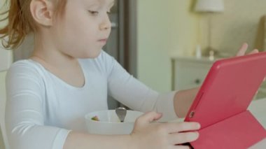 küçük kız yiyor ve bilgisayar tablet kullanarak çalış. örümcek ağı dalga köpüğü