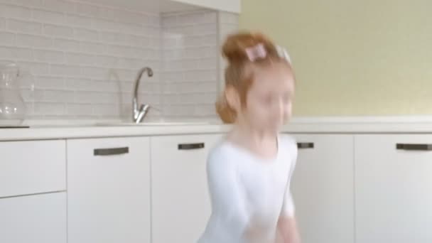 Una bambina felice in costume da bagno bianco da ginnastica, balli con nastro per ginnastica ritmica, salti ed esercizi professionali . — Video Stock